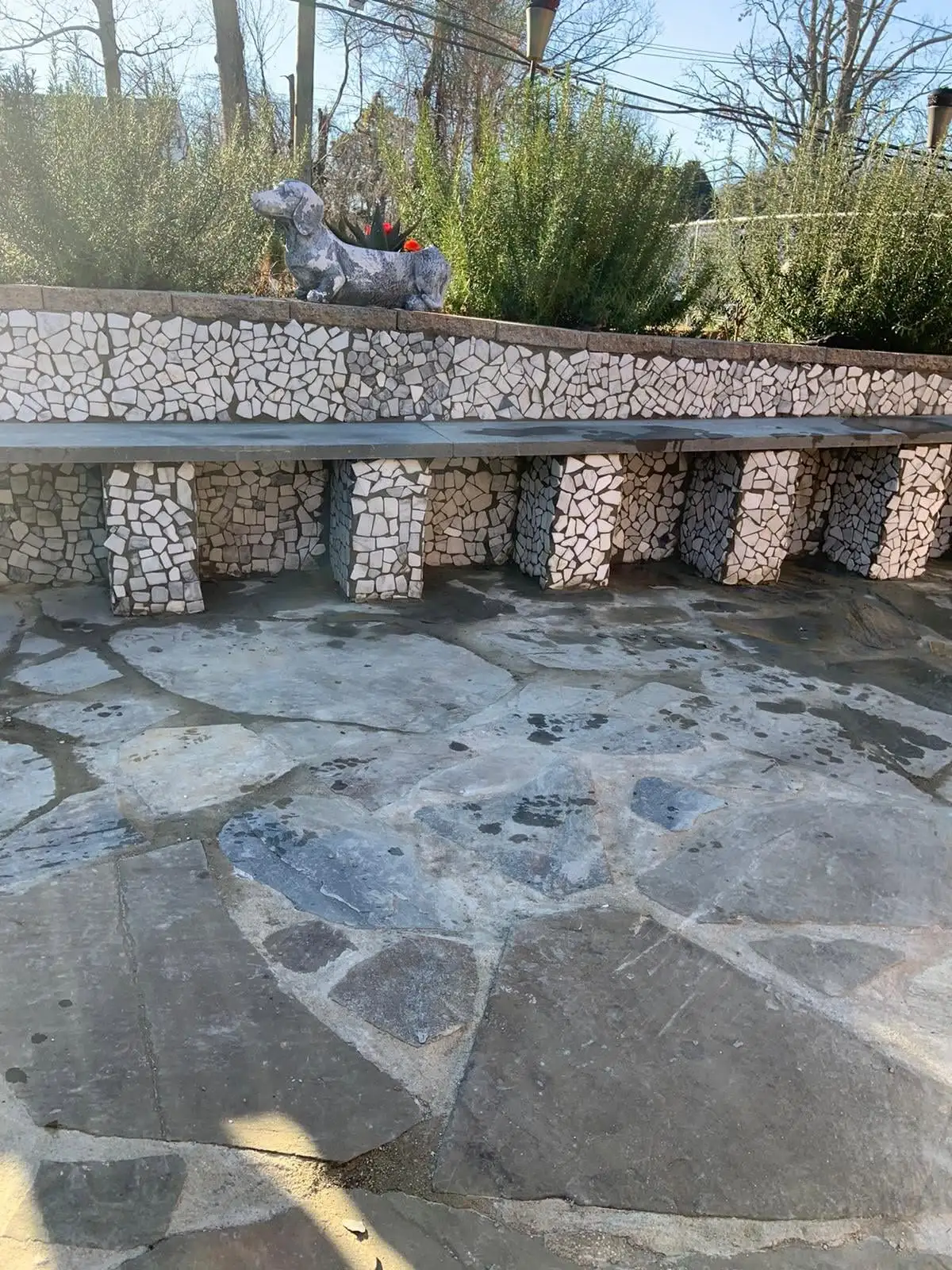 Decorative stone patio with mosaic bench wall
